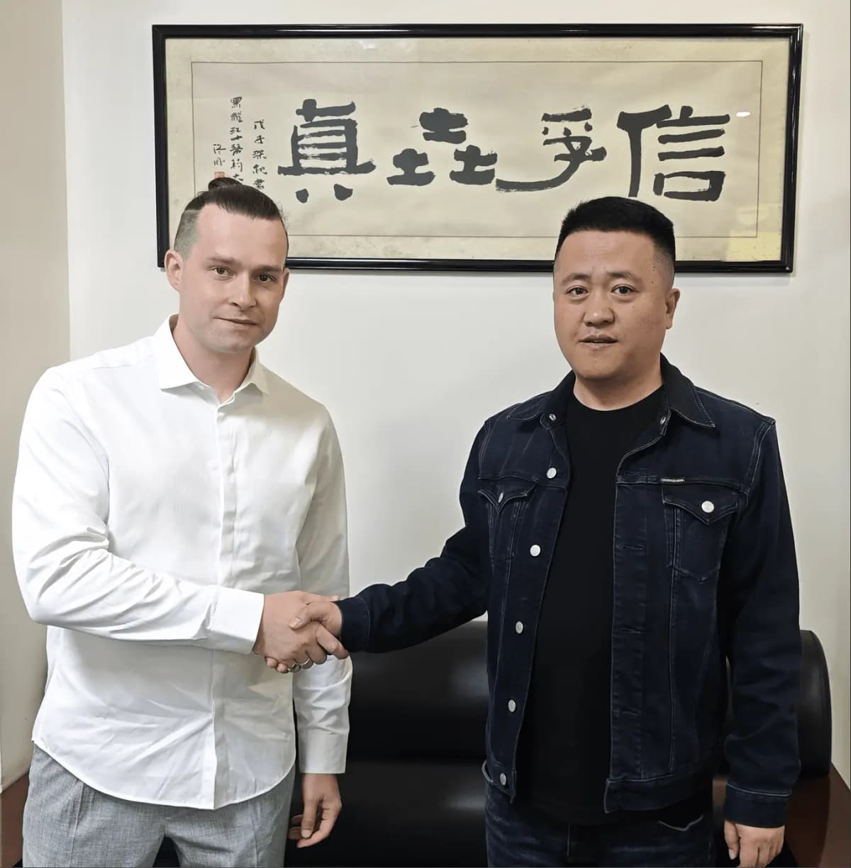 Стас Богословский с китайским партнёром под каллиграфией 信乎走真